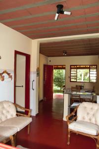 sala de estar con 2 sillas y puerta roja en Sitio Estrada Real de Tirandentes, en Santa Cruz de Minas