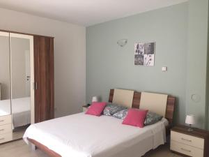a bedroom with a large white bed with pink pillows at Apartments Rube in Primošten