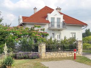 a white house with a fence and a red fire hydrant at Albízia Apartments in Balatonfüred