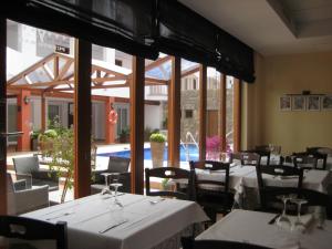 un ristorante con tavoli e sedie bianchi e una piscina di Aparthotel Puerto Mar a Peñíscola