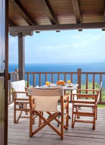 a table and chairs on a deck with a view of the ocean at Tampakeika in Mouresi