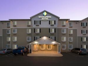 un gran edificio con coches estacionados en un estacionamiento en WoodSpring Suites Topeka en Topeka