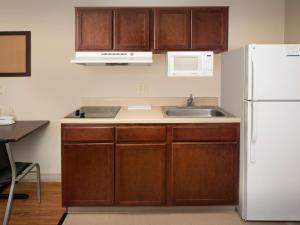 a kitchen with a white refrigerator and a sink at WoodSpring Suites Topeka in Topeka