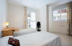 a bedroom with two beds and a desk and a window at Plaza de las Flores in Málaga