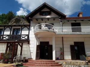 a white house with a balcony on top of it at Valcsics Villa Panzió in Pécs