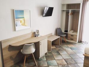 サンタ・マリア・アル・バーニョにあるHotel Coralloのデスク、椅子2脚、鏡が備わる客室です。