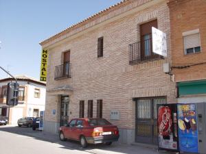 a red car parked in front of a brick building at Hostal Jalisco in Ajofrín