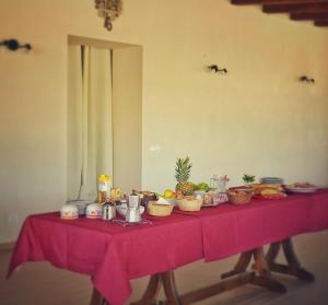 a table with a pink table cloth with food on it at Gelsomino B&B in Ispica