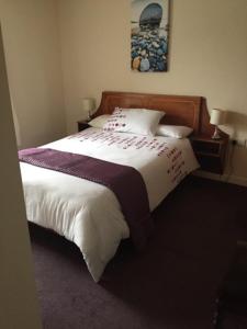 um quarto com uma cama com lençóis brancos e roxos em O'Loughlin's Bar em Miltown Malbay