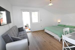 een slaapkamer met een bed, een bank en een tafel bij Apartment Helen in Ičići