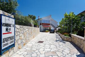 un panneau sur un mur en pierre à côté d'une maison dans l'établissement Villa Rosi, à Krk