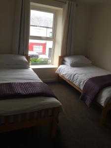 two beds in a room with a window at O'Loughlin's Bar in Miltown Malbay