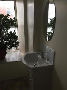 een badkamer met een wastafel, een spiegel en een raam bij O'Loughlin's Bar in Miltown Malbay