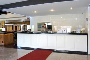 a man talking on a cell phone behind a counter at The Victoria Hotel Dunedin in Dunedin