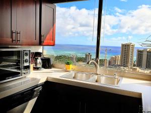 a kitchen with a sink and a view of the city at Hawaiian Monarch Penthouse 401 by Hawaii Ocean Club in Honolulu