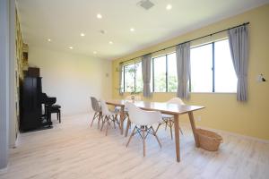 a dining room with a table and white chairs at Guesthouse ORI ORI in Niigata