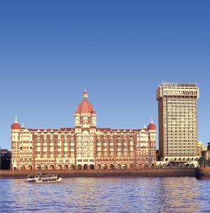 um grande edifício no rio com um barco na água em The Taj Mahal Palace, Mumbai em Mumbai