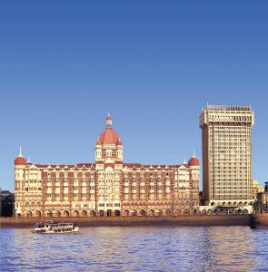 a large building on the river with a boat in the water at The Taj Mahal Palace, Mumbai in Mumbai