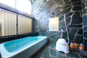 y baño con bañera en una pared de piedra. en Minshuku Fukufuji, en Nikko
