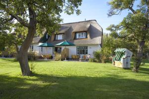 una casa con techo de paja y patio en Rackmers Hof - Suiten Hotel garni mit Sauna en Oevenum