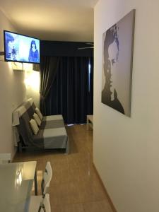 een woonkamer met een bank en een tv aan de muur bij Benal Beach Apartment in Benalmádena