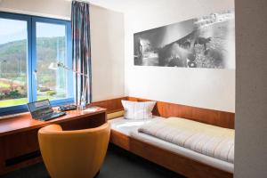 バート・ブランケンブルクにあるLandessportschule Bad Blankenburgのベッド、デスク、窓が備わる客室です。