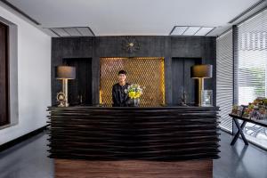 a man standing behind a reception desk in a lobby at Aruntara Riverside Boutique Hotel -SHA Extra Plus in Chiang Mai