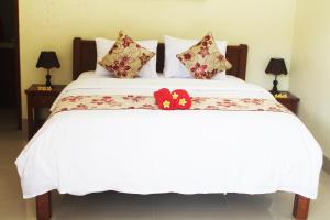 Una cama blanca con dos flores rojas. en Amed Kunara Guest House en Amed