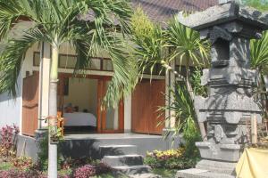 a building with palm trees in front of a building at Amed Kunara Guest House in Amed