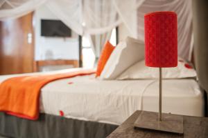 une lampe rouge sur une table à côté d'un lit dans l'établissement La Villa 126, à Dakar