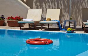 a red raft in a swimming pool with chairs at Studios Marios in Kamari
