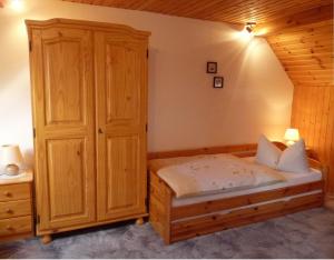 ワイマールにあるPension a la Kleinertのベッドルーム1室(ベッド1台付)、木製キャビネットが備わります。