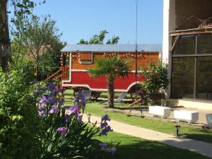 a red caravan is parked in a yard at Chambres et Roulotte de La Gentilhommière in Chazey-sur-Ain