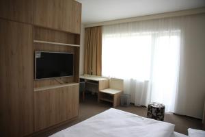 a hotel room with a bed and a television and a desk at Hotel Devítka in Hřensko