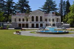 a large house with a fountain in front of it at Comfortable Apartment close to Central Park in Tsqaltubo