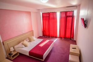 a small bedroom with a bed and red curtains at Hotel Vis in Eforie Nord