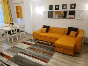 ブカレストにあるFundeni Apartmentsのリビングルーム(オレンジ色のソファ、テーブル付)