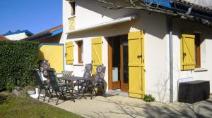 a house with yellow doors and a table and chairs at Park Village Océlandes in Saint-Julien-en-Born