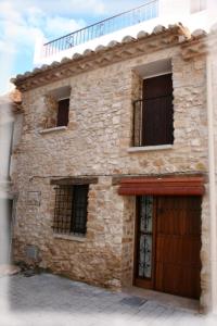 - un vieux bâtiment en pierre avec une porte et des fenêtres dans l'établissement Casa La Vileta - Turistrat, à Albocácer