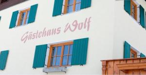 un edificio bianco con finestre verdi e un cartello sopra di Gastehaus Wolf a Bach