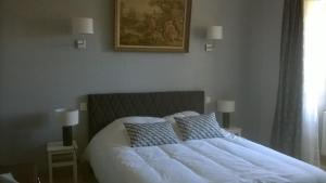 uma cama com lençóis brancos e almofadas num quarto em lembaudie em Saint-Privat-des-Prés