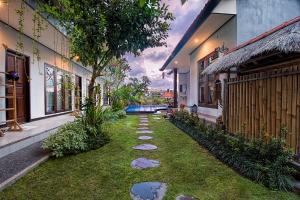 a garden with rocks in the grass between two buildings at Bali Full Moon Guest House in Canggu