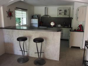 a kitchen with a counter with two stools at Les Gites du Mas des Cigales in Nîmes