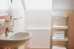 a bathroom with a sink and a radiator and towels at Penzión Kúria in Nové Mesto nad Váhom