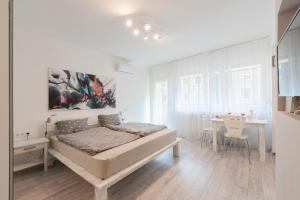 a white bedroom with a bed and a table at Casa Tua3 in Budapest