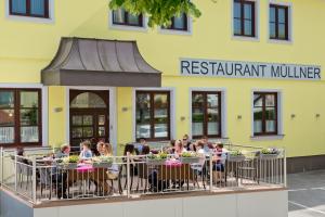 un groupe de personnes assises à une table à l'extérieur d'un restaurant dans l'établissement Hotel Restaurant Müllner, à Marz