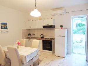 a kitchen with a table and a white refrigerator at Apartments Jelena in Pag