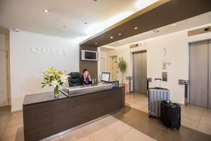 a woman sitting at a reception desk in a hotel lobby at Quest On Lambton Serviced Apartments in Wellington