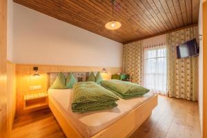 um quarto com 2 camas e almofadas verdes em Berggasthaus Agritur Moserhof em Braies (Prags)