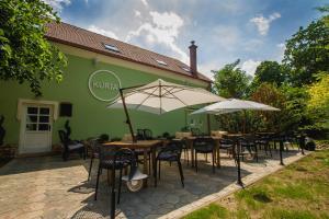 a group of tables and chairs with umbrellas in front of a building at Penzión Kúria in Nové Mesto nad Váhom